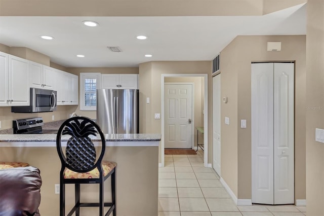 kitchen featuring visible vents, a kitchen breakfast bar, white cabinetry, stainless steel appliances, and a peninsula