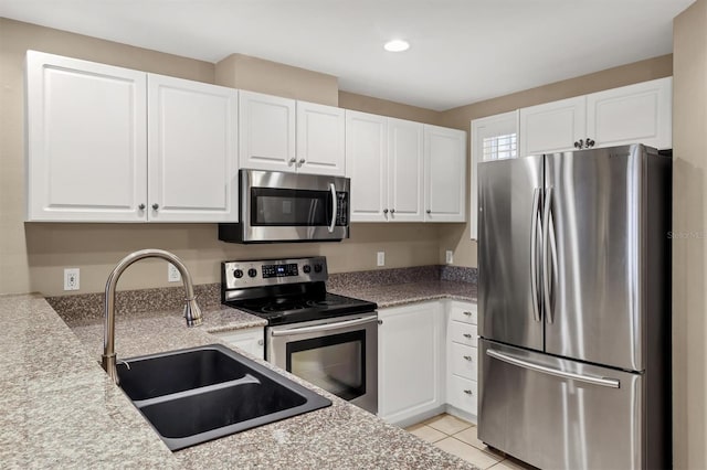 kitchen with light countertops, appliances with stainless steel finishes, light tile patterned flooring, white cabinets, and a sink