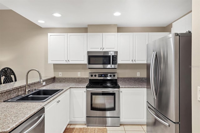 kitchen with light tile patterned floors, recessed lighting, a sink, stainless steel appliances, and white cabinets