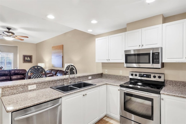 kitchen featuring a peninsula, ceiling fan, a sink, appliances with stainless steel finishes, and open floor plan