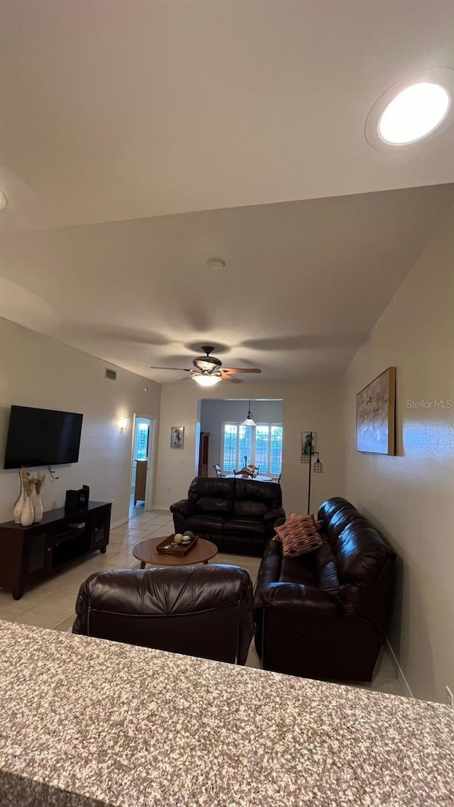 living area featuring light tile patterned floors, visible vents, and ceiling fan