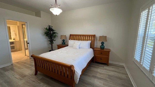 bedroom featuring multiple windows, connected bathroom, baseboards, and wood finished floors