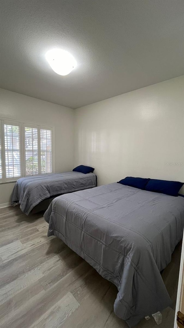 bedroom with a textured ceiling and wood finished floors