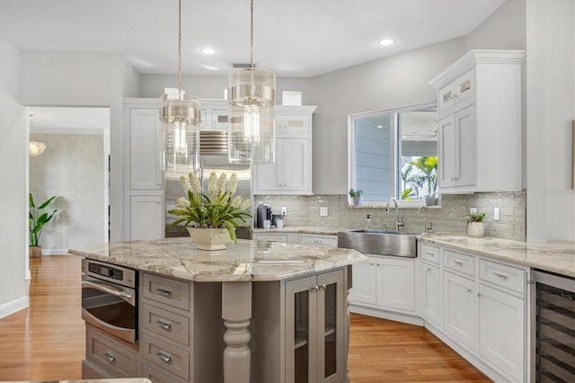 810 Siesta Dr, Sarasota, FL 34242 - kitchen featuring a sink, beverage cooler, light wood-type flooring, tasteful backsplash, and recessed lighting