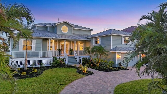 810 Siesta Dr, Sarasota, FL 34242 - view of front facade with covered porch, decorative driveway, metal roof, a front lawn, and a garage