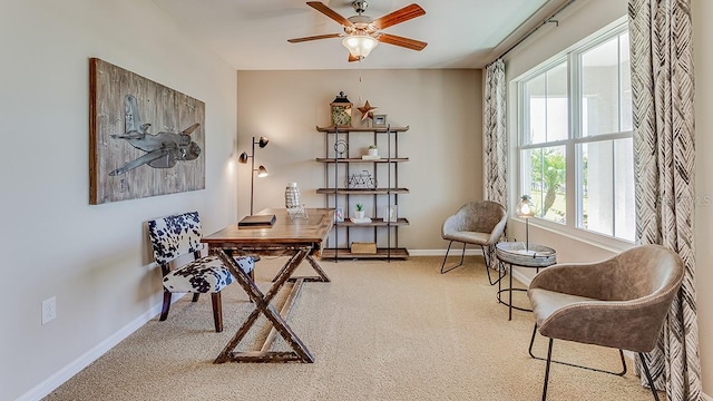 carpeted office space featuring a ceiling fan and baseboards