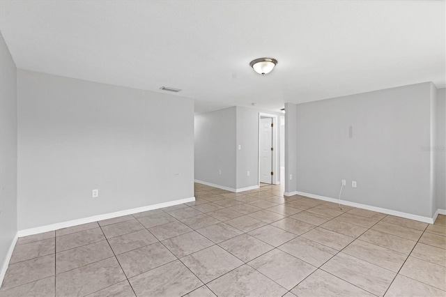 unfurnished room with light tile patterned floors, visible vents, and baseboards