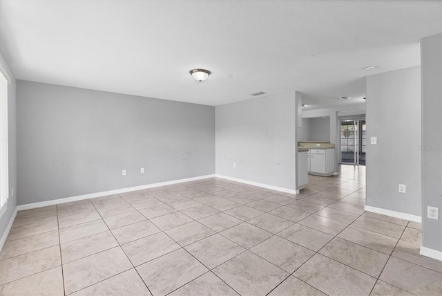 empty room with light tile patterned floors and baseboards