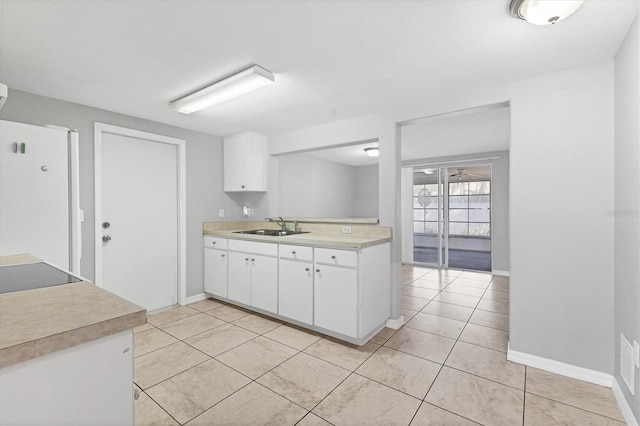 kitchen featuring light tile patterned flooring, freestanding refrigerator, a sink, light countertops, and white cabinets