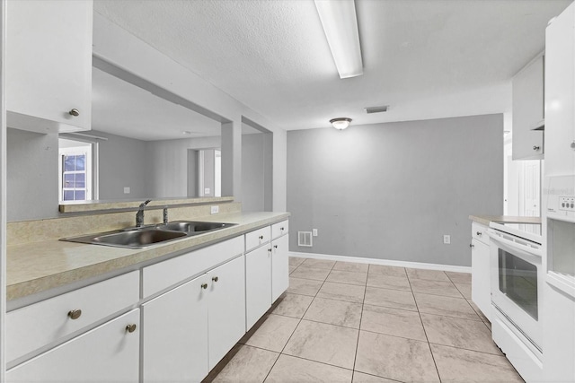 kitchen featuring visible vents, electric stove, a sink, white cabinets, and light countertops