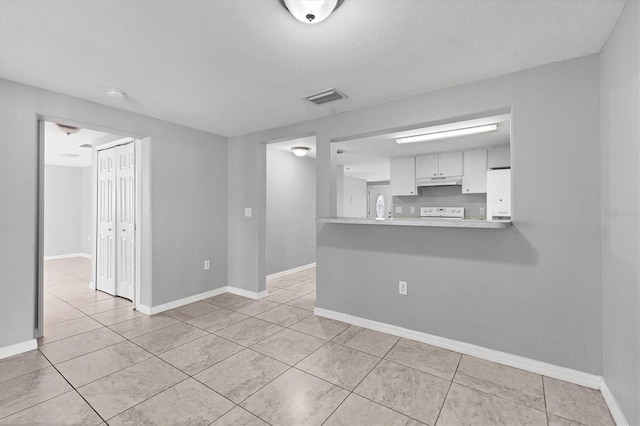 empty room with light tile patterned flooring, baseboards, and visible vents