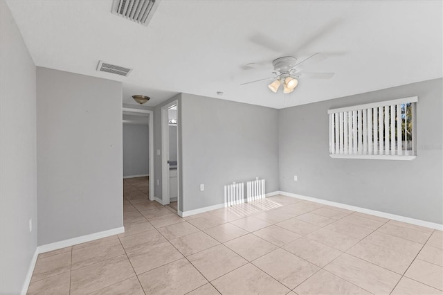 empty room featuring tile patterned floors, baseboards, visible vents, and ceiling fan