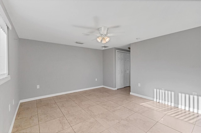 tiled spare room with visible vents, baseboards, and a ceiling fan