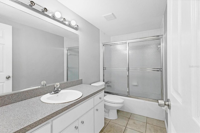 full bathroom with visible vents, toilet, tile patterned floors, combined bath / shower with glass door, and vanity