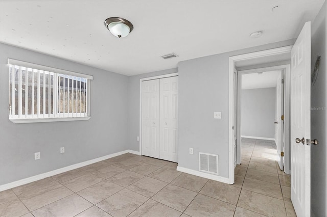 unfurnished bedroom with visible vents, baseboards, a closet, and tile patterned flooring