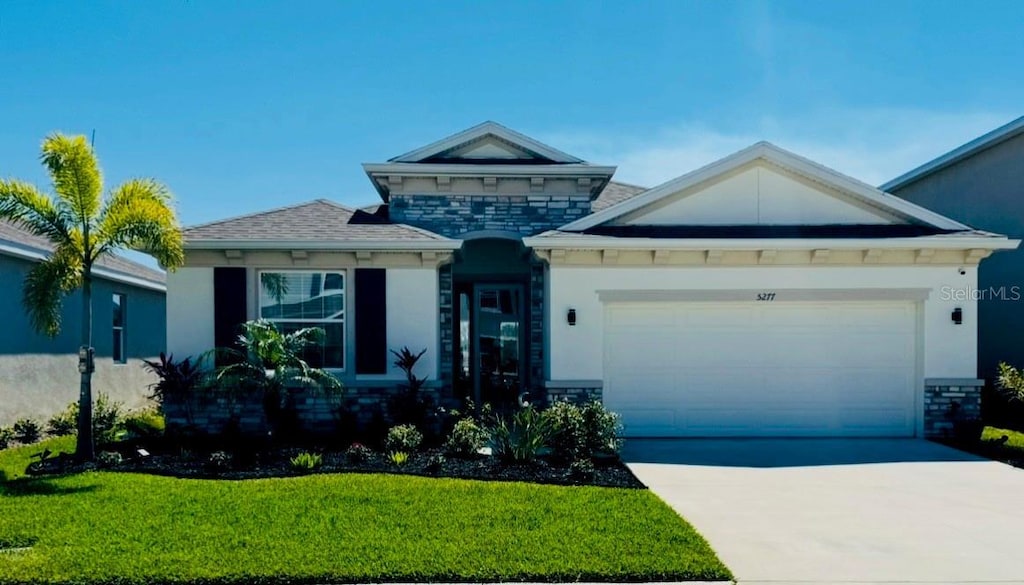 view of front of house featuring a front lawn, concrete driveway, stucco siding, stone siding, and an attached garage