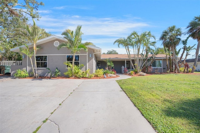 ranch-style house with stucco siding, concrete driveway, and a front lawn