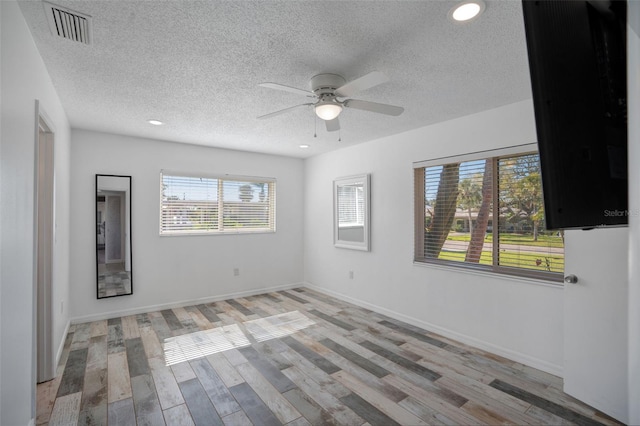 empty room with baseboards, visible vents, light wood finished floors, and ceiling fan