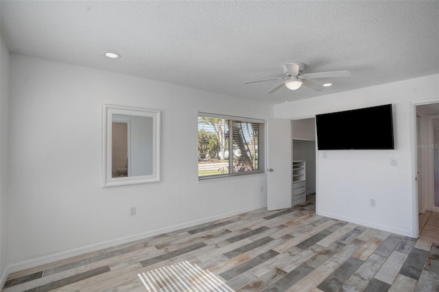 spare room with baseboards, a textured ceiling, a ceiling fan, and light wood-style floors