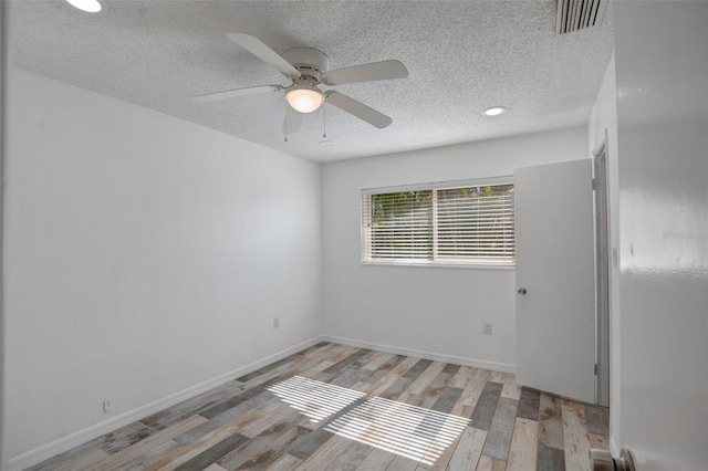 unfurnished room featuring visible vents, light wood-style flooring, a ceiling fan, a textured ceiling, and baseboards