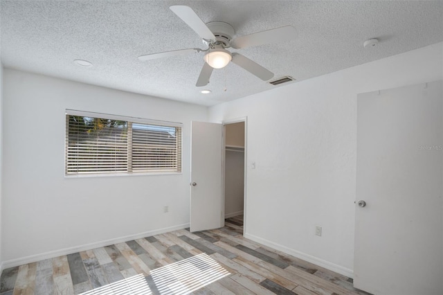 unfurnished bedroom featuring visible vents, a ceiling fan, a textured ceiling, light wood-style floors, and baseboards