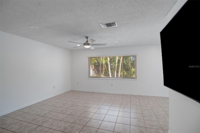 unfurnished room with visible vents, a ceiling fan, a textured ceiling, light tile patterned floors, and baseboards