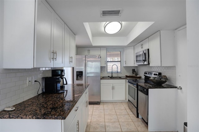 kitchen with visible vents, a tray ceiling, a sink, appliances with stainless steel finishes, and tasteful backsplash