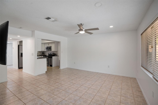 unfurnished living room featuring visible vents, a textured ceiling, light tile patterned flooring, baseboards, and ceiling fan