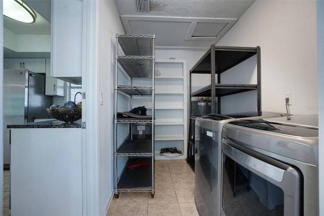 interior space featuring visible vents, attic access, laundry area, light tile patterned flooring, and washer and dryer