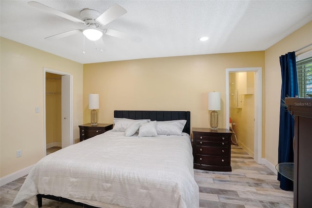 bedroom with light wood-type flooring, baseboards, a textured ceiling, and ceiling fan