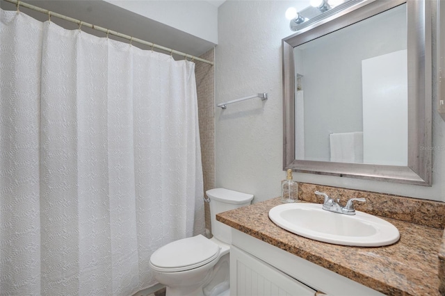 bathroom featuring toilet, vanity, and a textured wall