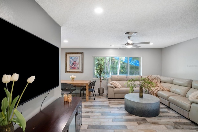 living room featuring visible vents, light wood-type flooring, recessed lighting, a textured ceiling, and a ceiling fan