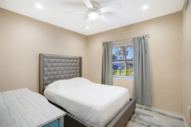 bedroom featuring visible vents, ceiling fan, baseboards, light wood-style floors, and a textured wall