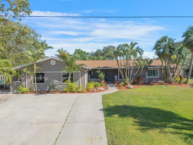 single story home featuring stucco siding, a front yard, and driveway