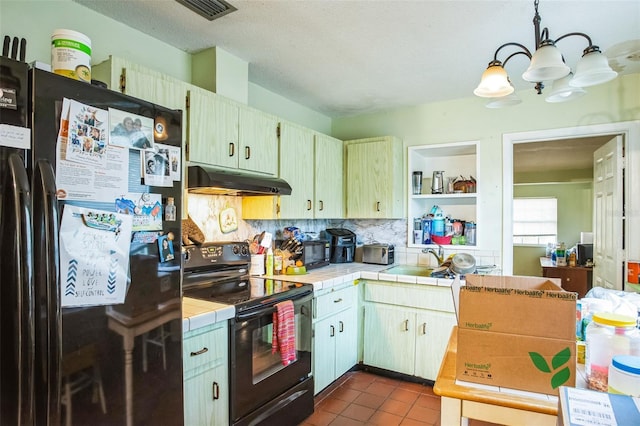 kitchen with decorative backsplash, black appliances, tile counters, under cabinet range hood, and dark tile patterned floors