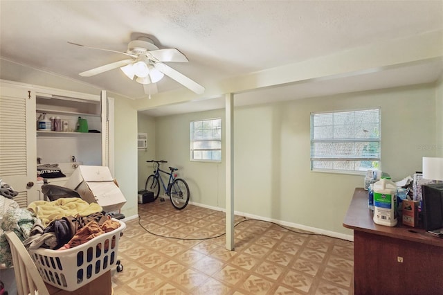 interior space featuring baseboards, light floors, ceiling fan, and a textured ceiling