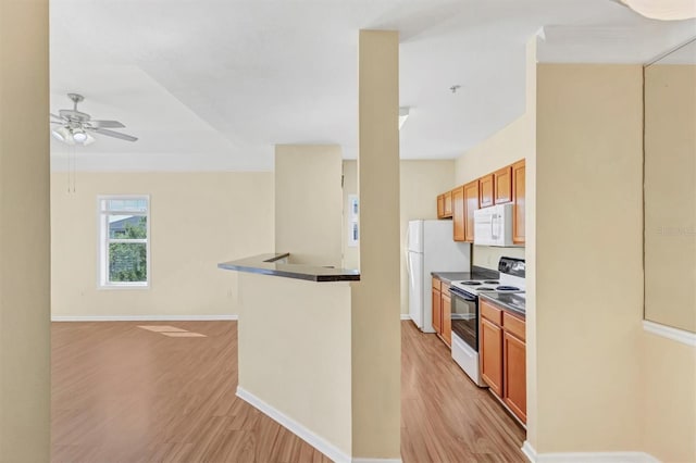 kitchen featuring dark countertops, open floor plan, light wood-style flooring, and white appliances