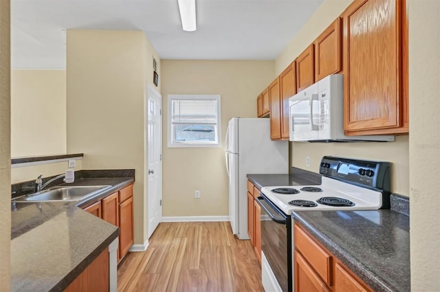 kitchen featuring light wood-style flooring, a sink, electric range oven, baseboards, and white microwave