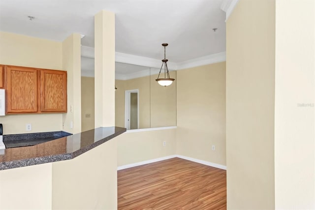 kitchen with ornamental molding, light wood finished floors, baseboards, white microwave, and hanging light fixtures