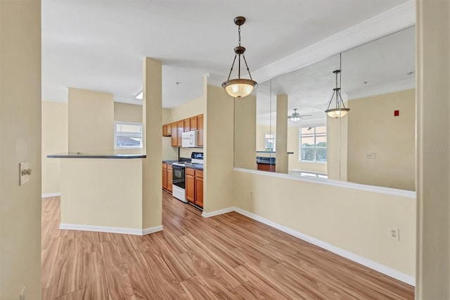 kitchen featuring white microwave, baseboards, light wood finished floors, hanging light fixtures, and range with electric stovetop