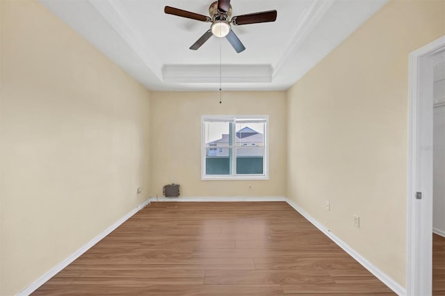 unfurnished room featuring a ceiling fan, a raised ceiling, baseboards, and wood finished floors