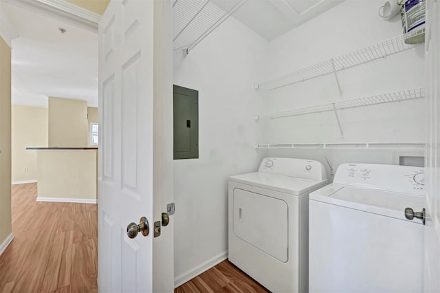 laundry area featuring baseboards, electric panel, laundry area, wood finished floors, and independent washer and dryer