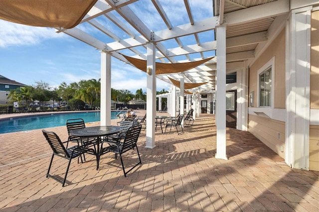 view of patio featuring a community pool, fence, and a pergola