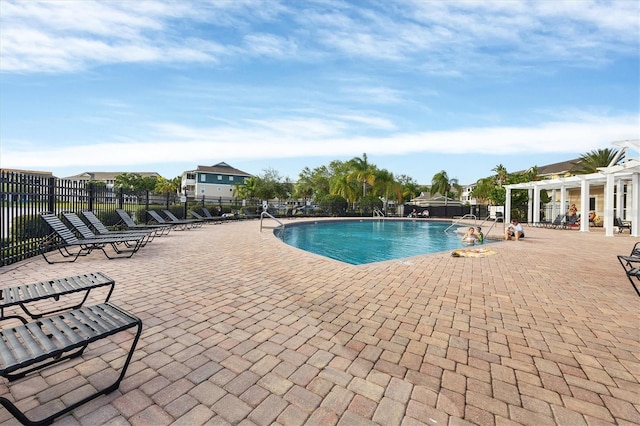 community pool with a patio area, a pergola, and fence