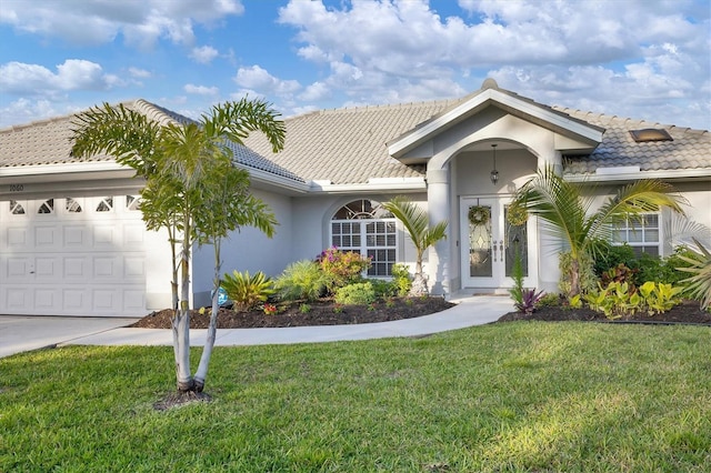 view of front of house featuring a front lawn, a tiled roof, stucco siding, french doors, and a garage