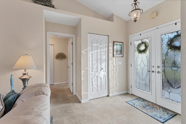 foyer featuring vaulted ceiling, light tile patterned flooring, french doors, and baseboards