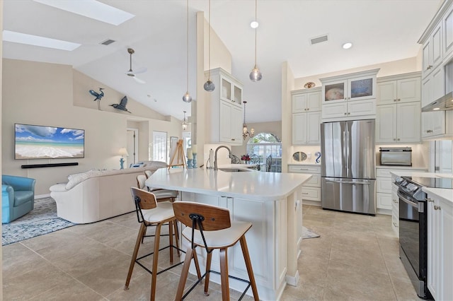 kitchen featuring open floor plan, range with electric stovetop, a peninsula, freestanding refrigerator, and a kitchen breakfast bar