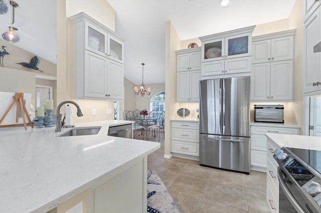 kitchen with light stone countertops, pendant lighting, a notable chandelier, stainless steel appliances, and a sink