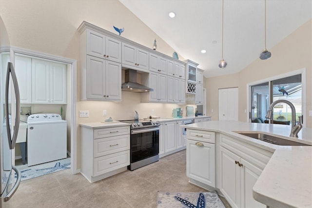 kitchen with wall chimney range hood, washer / dryer, appliances with stainless steel finishes, hanging light fixtures, and a sink