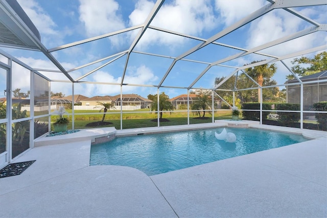 outdoor pool with glass enclosure, a patio, and a yard